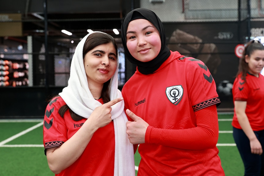 Adiba and Malala pose for a photo together wearing the uniform of the Afghan Women's Team