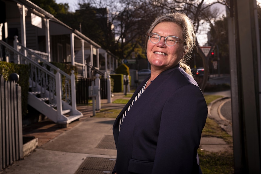 A woman next to a row of Queenslander houses