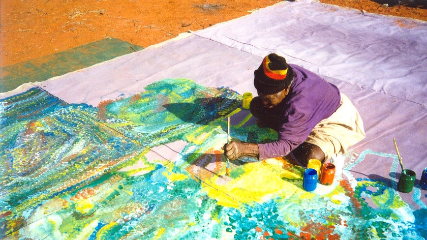 Emily Kngwarreye sits on the floor painting Earth's Creation 1.