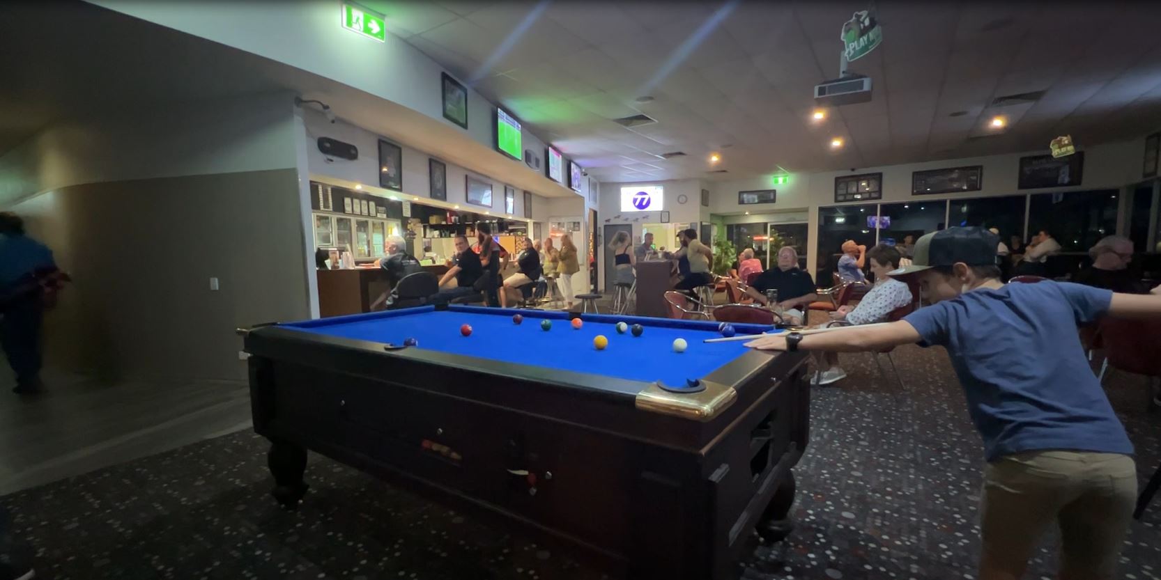A kid plays pool at an outback pub