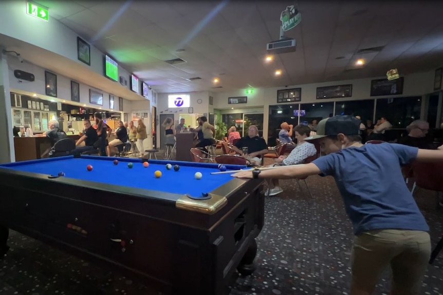 A kid plays pool at an outback pub