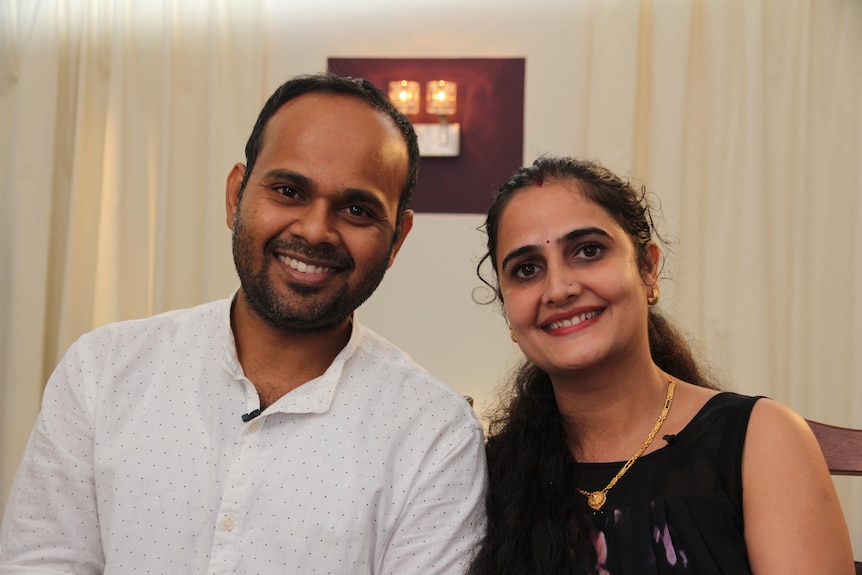 Indian husband and wife smiling at the camera. 