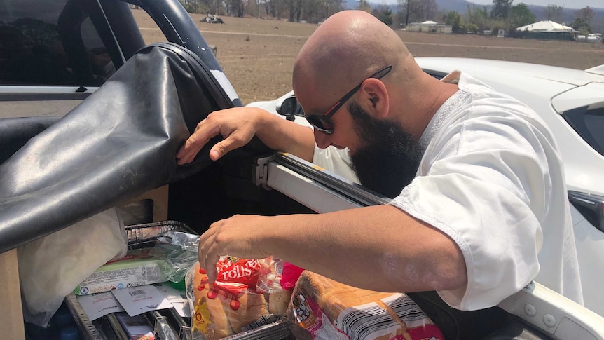 A man gets food out of the back of a ute