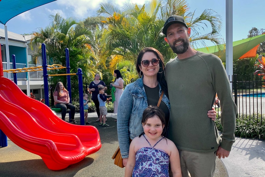 A family smile while standing in a playground.