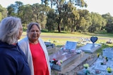 Two older Noongar ladies overlook tombstones at a cemetery