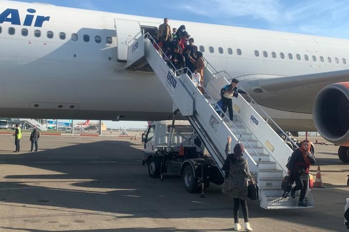 A group of people walk down some stairs after getting off a plane.