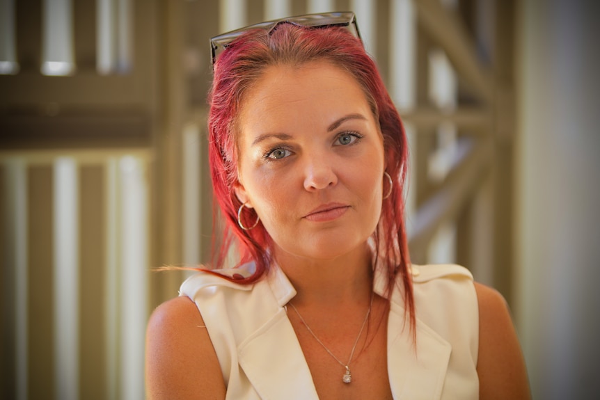 Woman wearing a white top with bright pink hair.