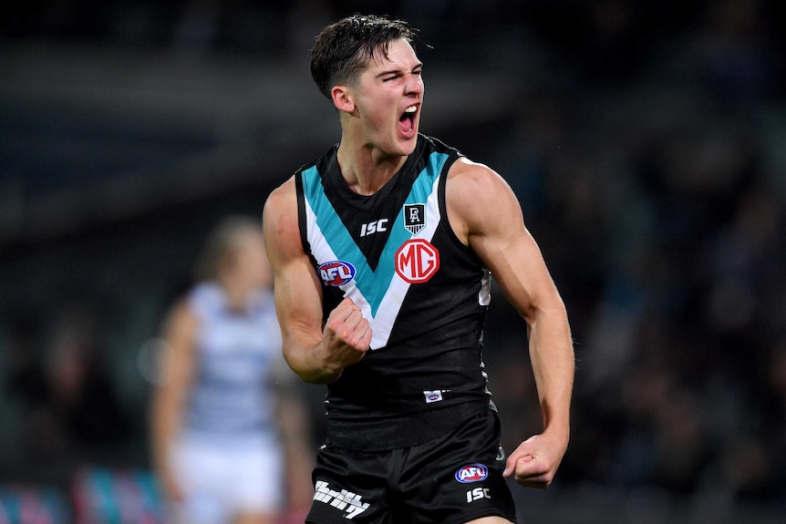 A Port Adelaide AFL player pumps his right fist as he celebrates kicking a goal against Geelong.