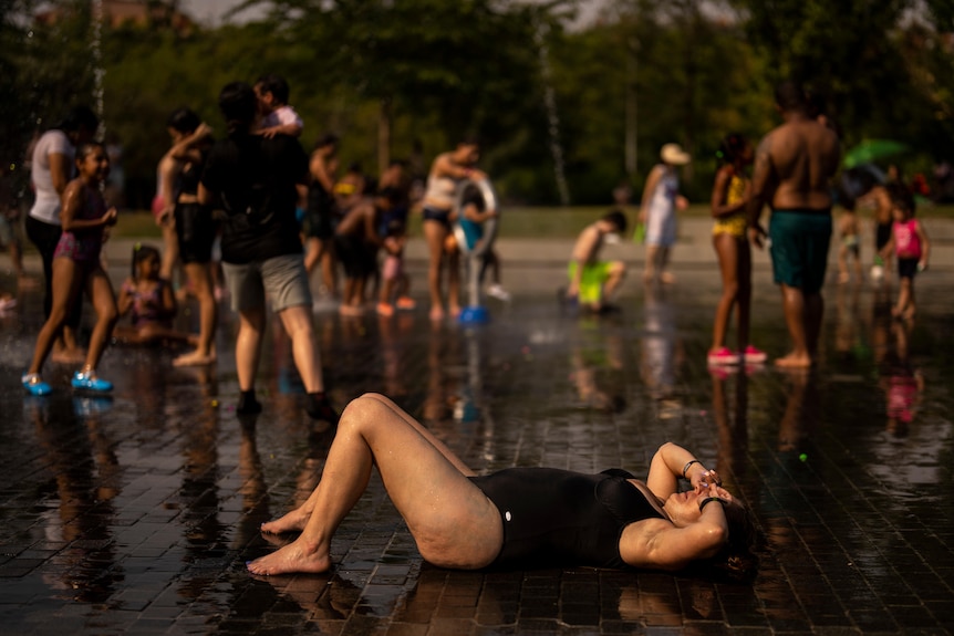Une femme en maillot de bain est allongée sur le sol, se tenant le visage.