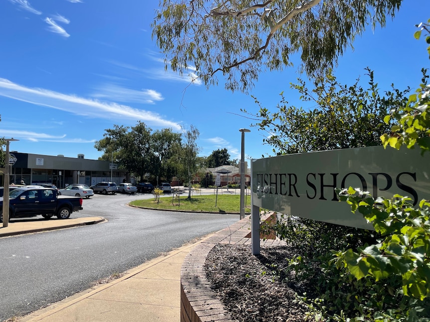 The entrance to local shops has a sign reading 'Fisher Shops'