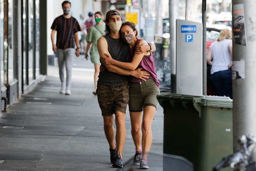 A couple embrace while walking