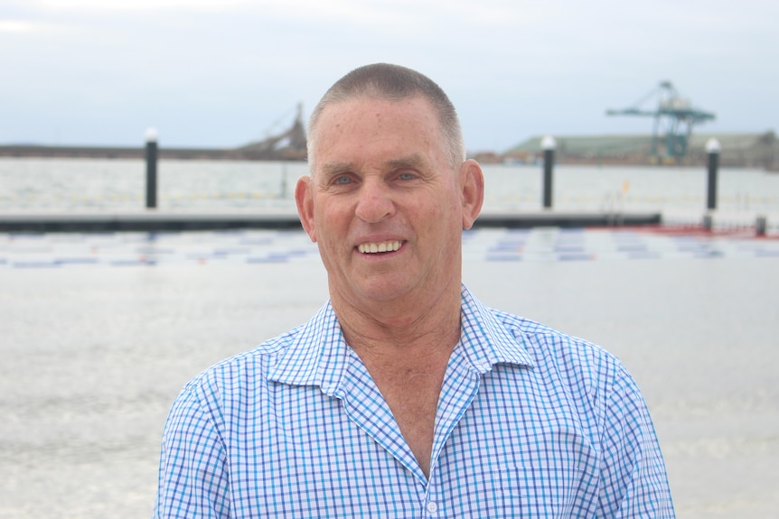 He stands in a shirt on the beach, in front of the new structure