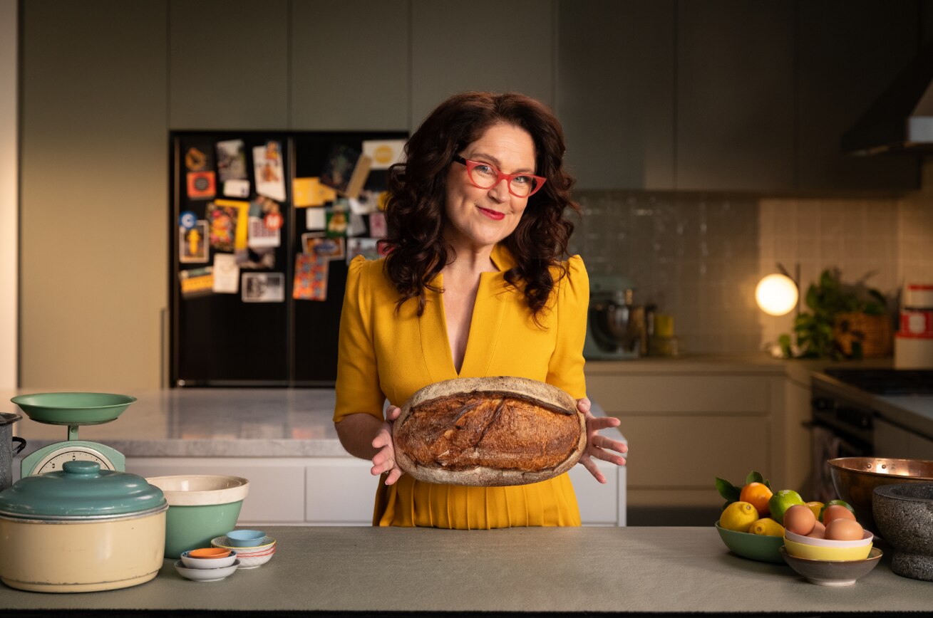 Annabel Crabb holding a sourdough loaf with parliament house drawn on it