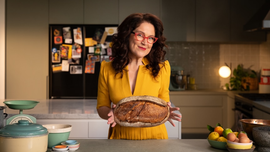 Annabel Crabb holding a sourdough loaf with parliament house drawn on it