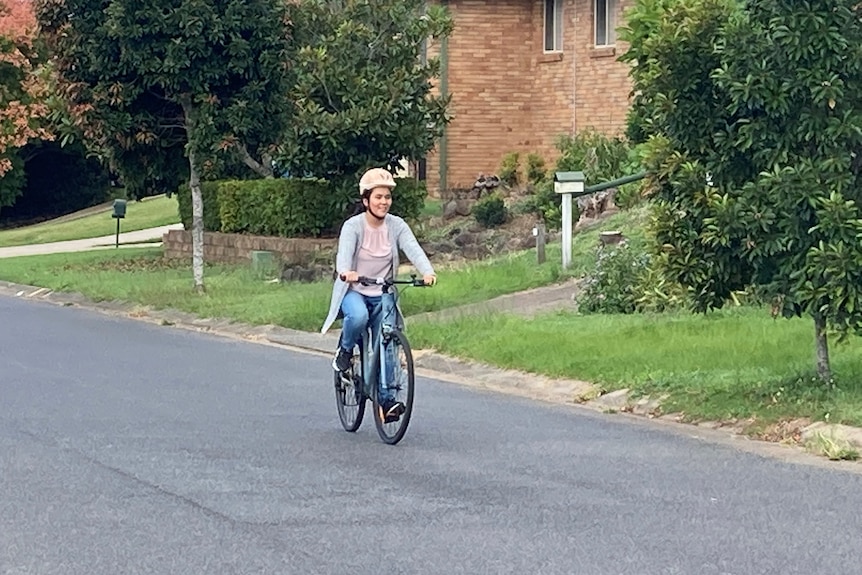 A girl in jeans riding a bike