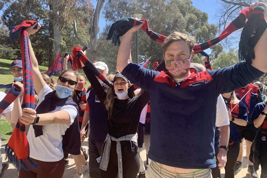 Fans smile in the sun and celebrate the Dees victory