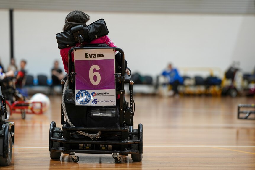 A shot taken from behind of Rebecca Evans on court in her powerchair.
