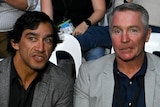 Johnathan Thurston talks to Paul Green while they sit in white plastic chairs to watch a boxing bout.