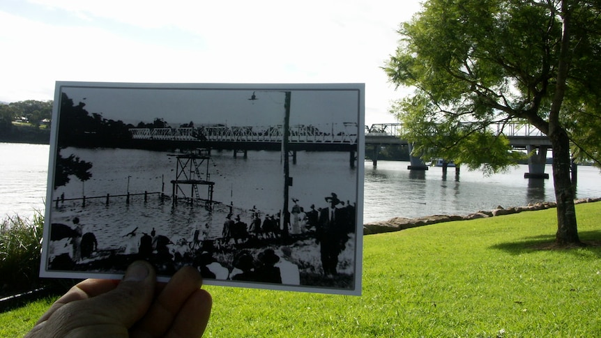 A black and white photo of Shoalhaven swimming pool is held up in front of a modern day look of the river.