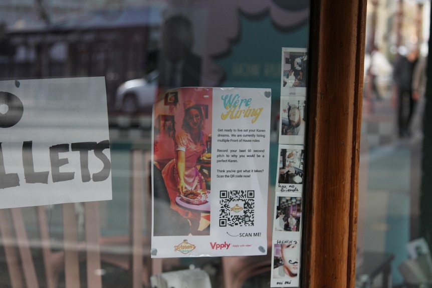 A close up of the window in Karen's Diner with a poster looking for staff