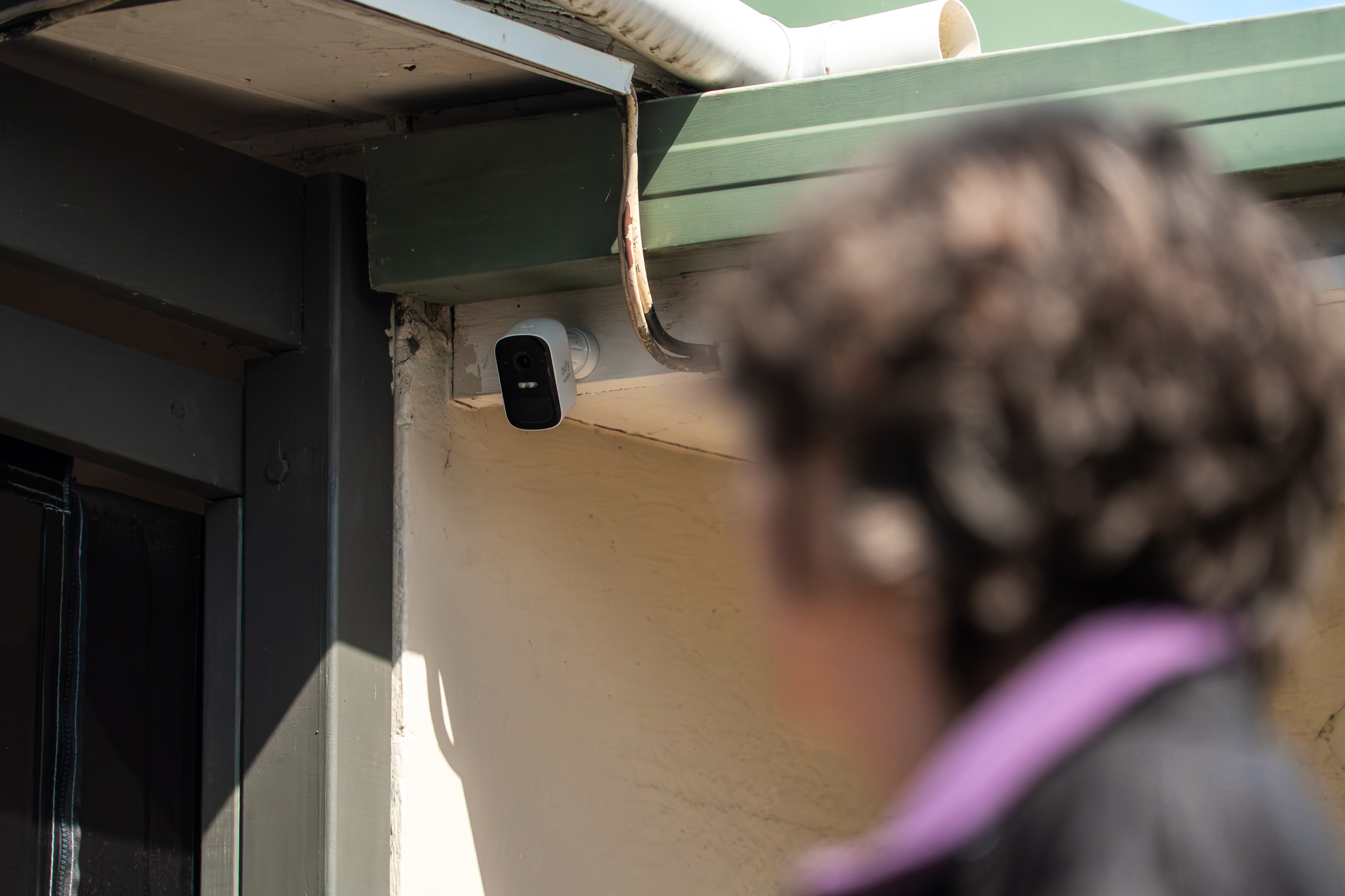 A woman looks at a security camera at a residential property.