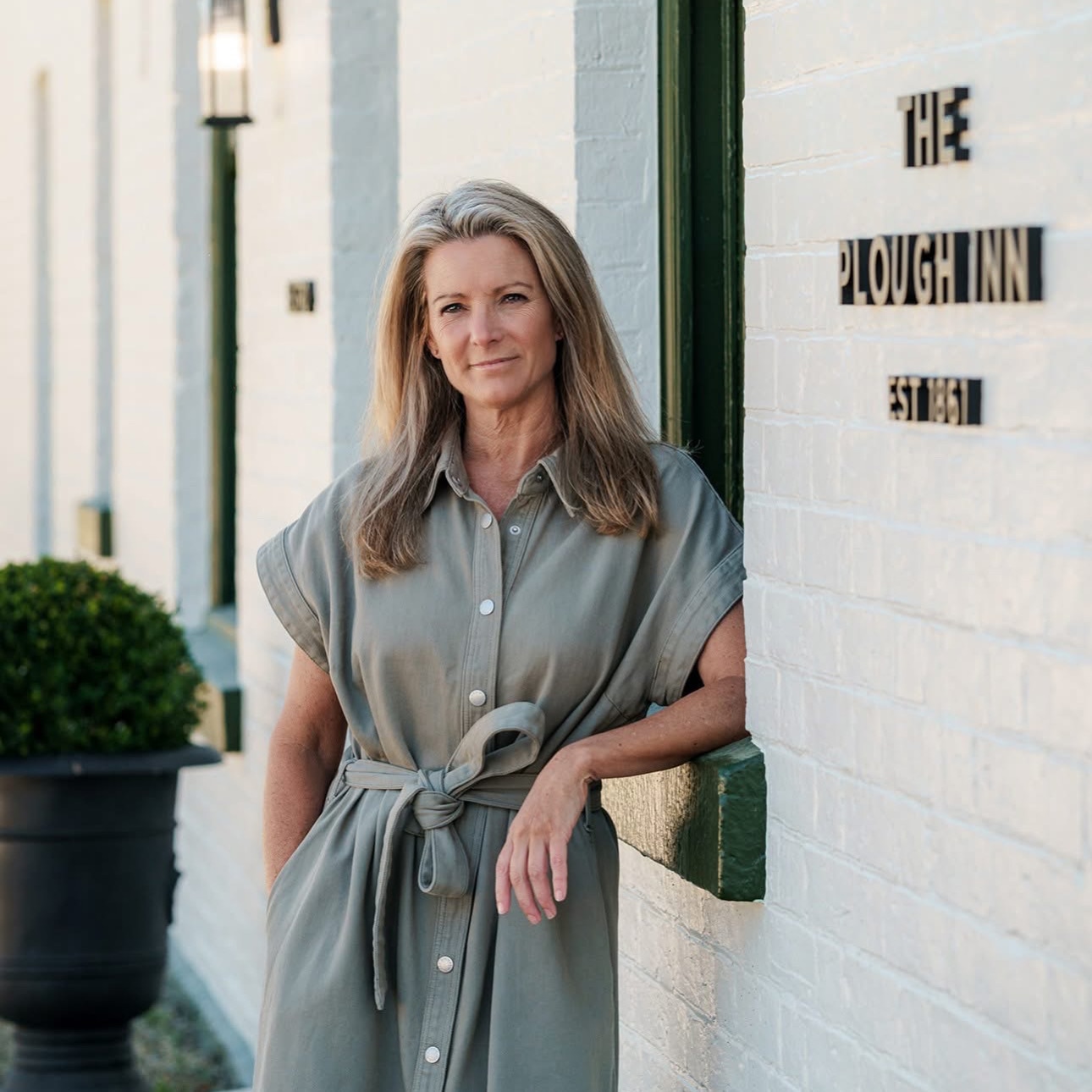 Peta Donaldson in green dress leaning up against building.
