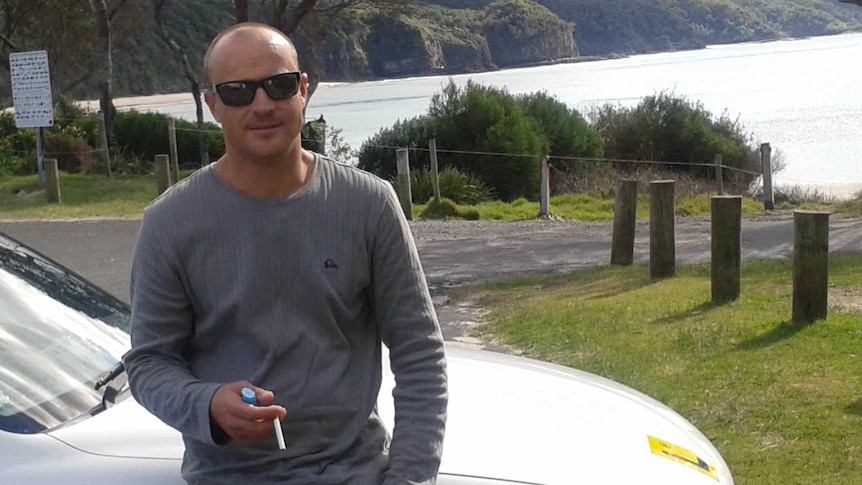 Todd McKenzie, who was fatally shot by police in Taree in 2019, stands in front of a car by the beach.