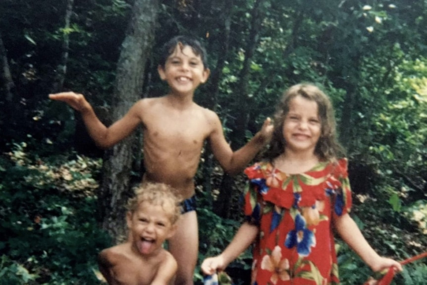 A film photo of three kids laughing and smiling at the camera