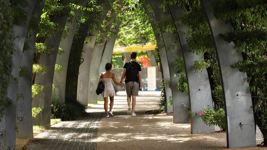 A couple walk together under the Grand Arbor in Brisbane's South Bank parklands.
