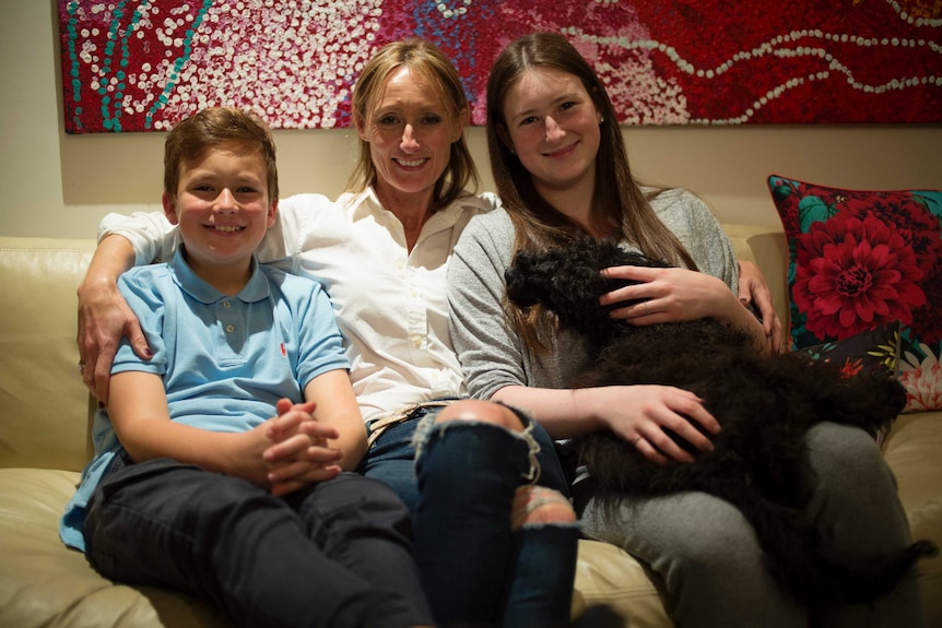 Van, Maryanne and Josie Larkin sit on their couch.