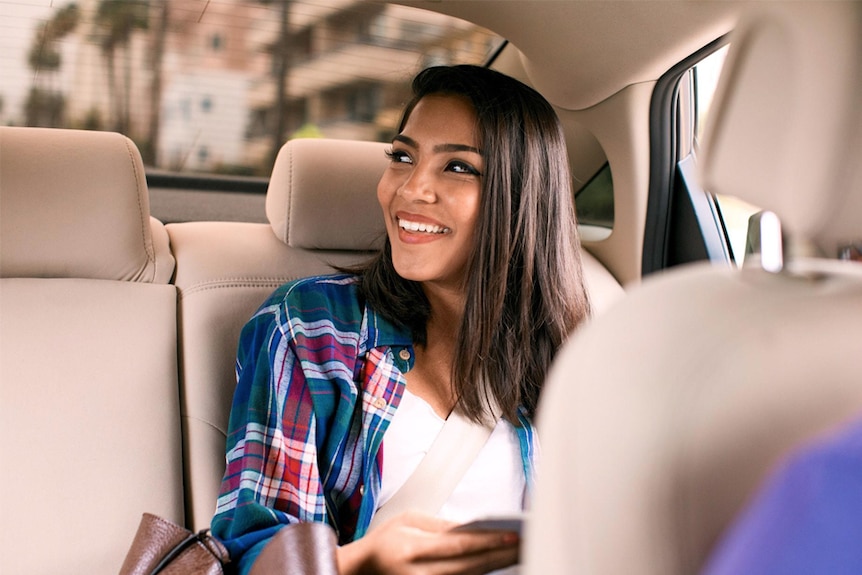 A woman rides in the back seat of an Uber car.