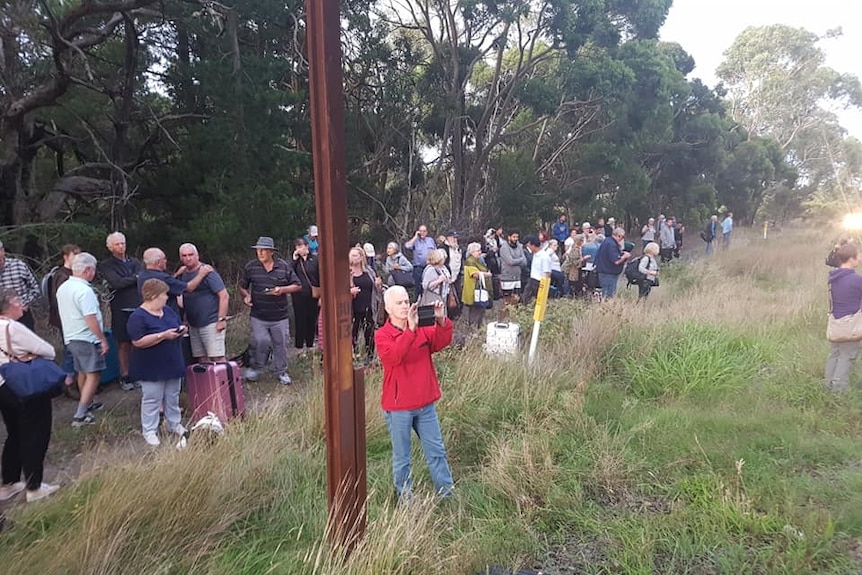 People standing on the side of the train tracks