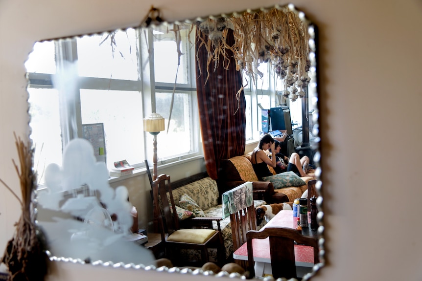 Photo of a mirror that shows two women sitting on a couch.