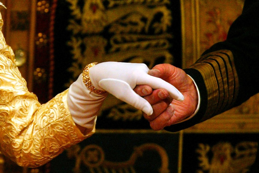 The Queen's gloved hand is held by Prince Philip.