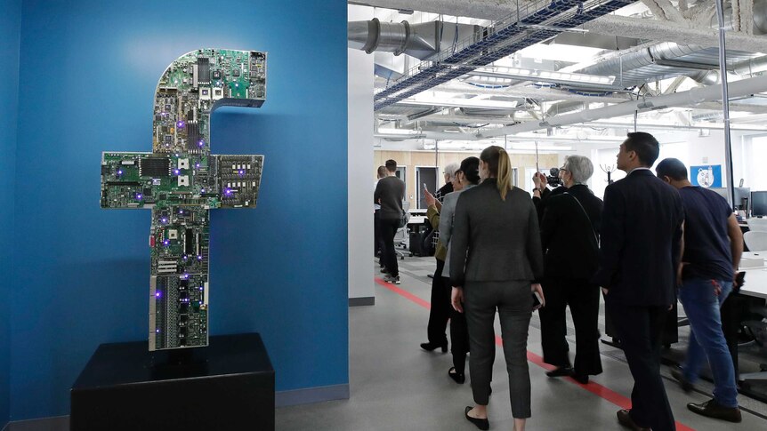 A group o people are touring a spares-looking office for Facebook