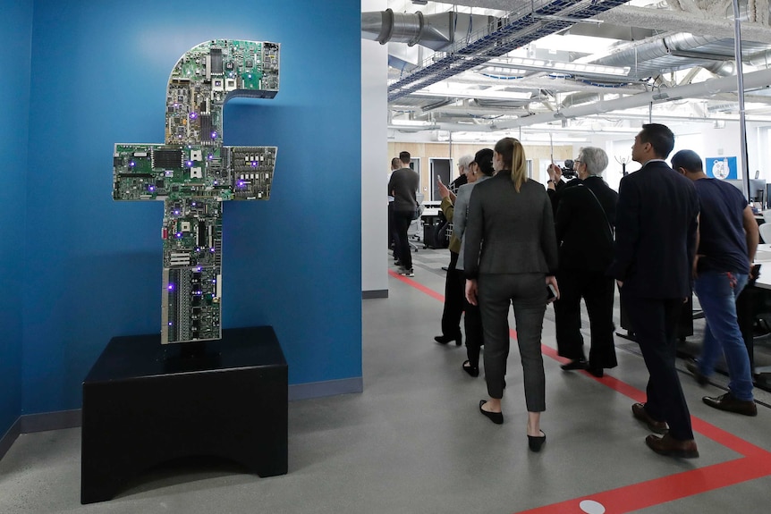 A group of people walk through a sparse-looking Facebook office