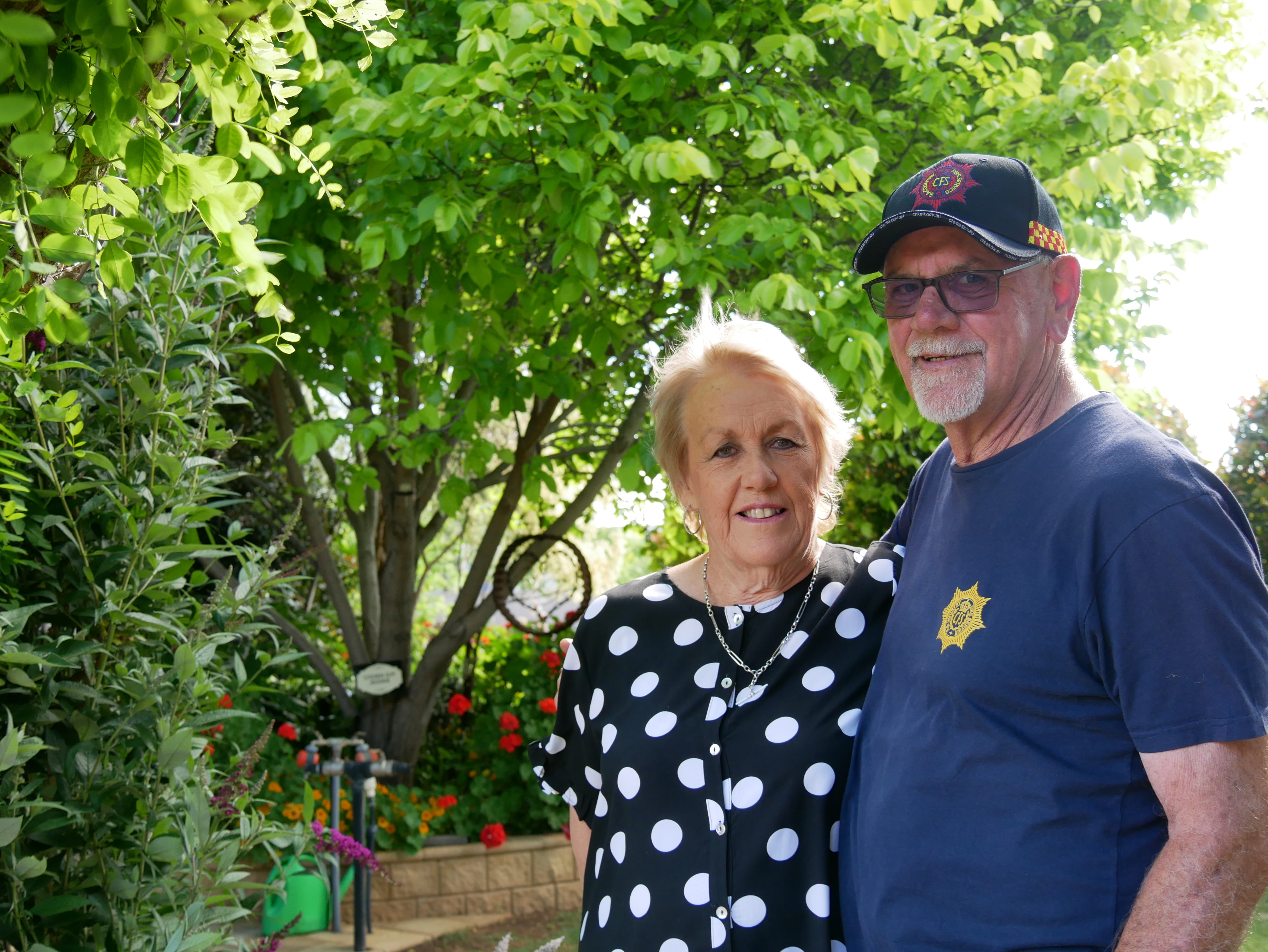 An older woman and man stand with their arms around each other.