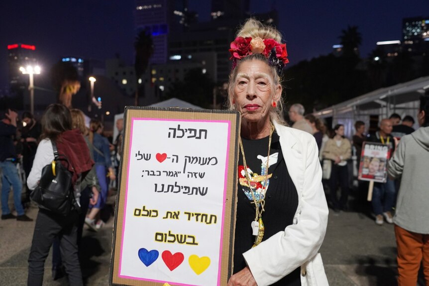 A woman holding a sign with Hebrew writing on it