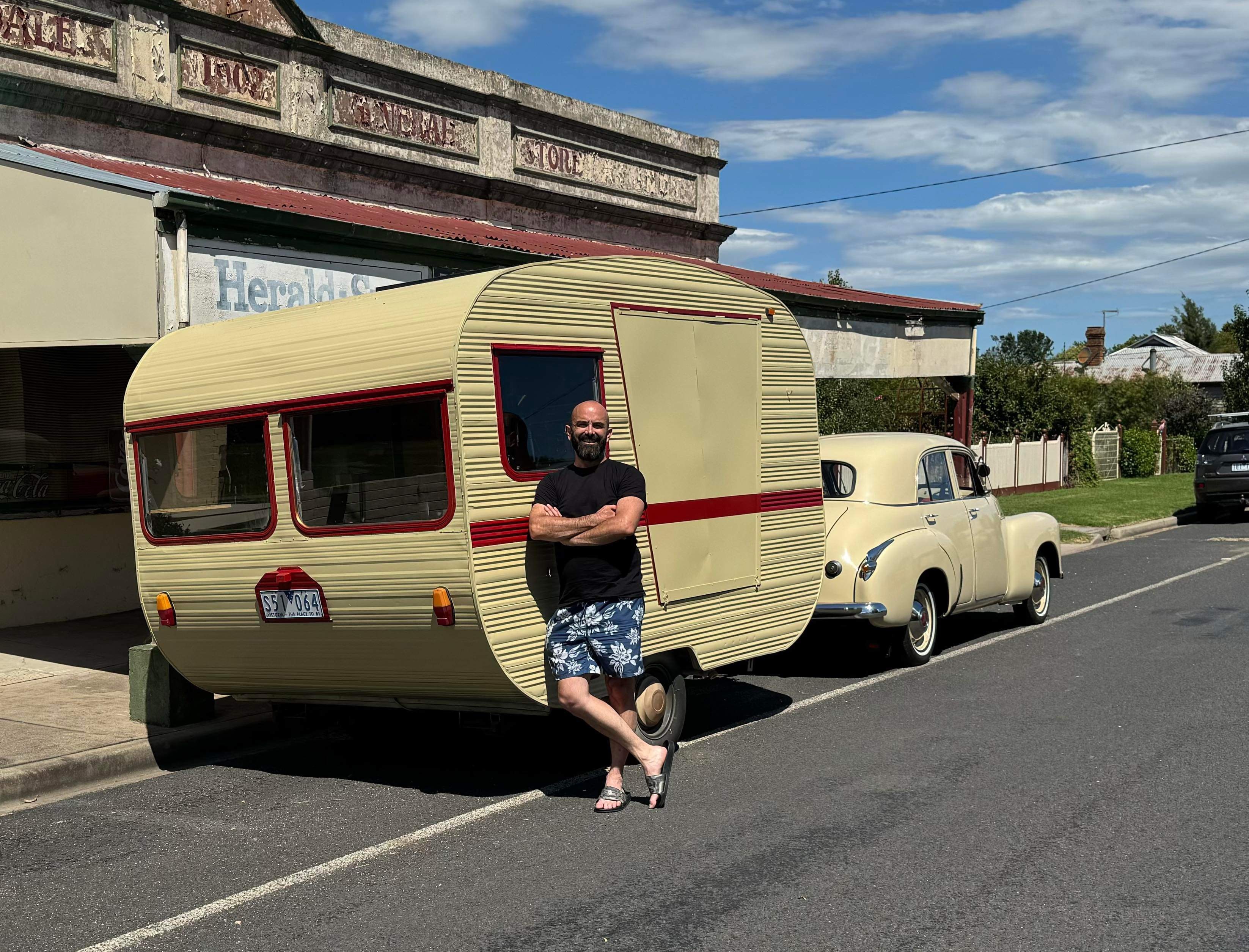 A man crossing his arms and leaning against his caravan. 