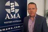Dr Andrew Miller AMA WA president stands in front of an AMA sign.