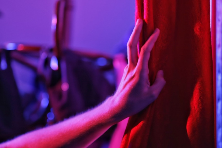 A hand on a red curtain.