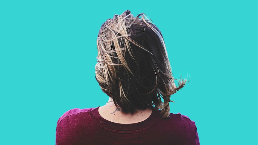 The back of a woman's head with shoulder length hair on a blue background