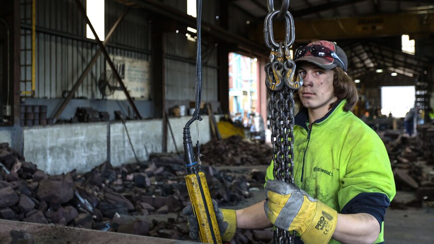 Justin McKeone, who just turned 17, began fulltime work last year as a labourer is pictured holding some metal chains.