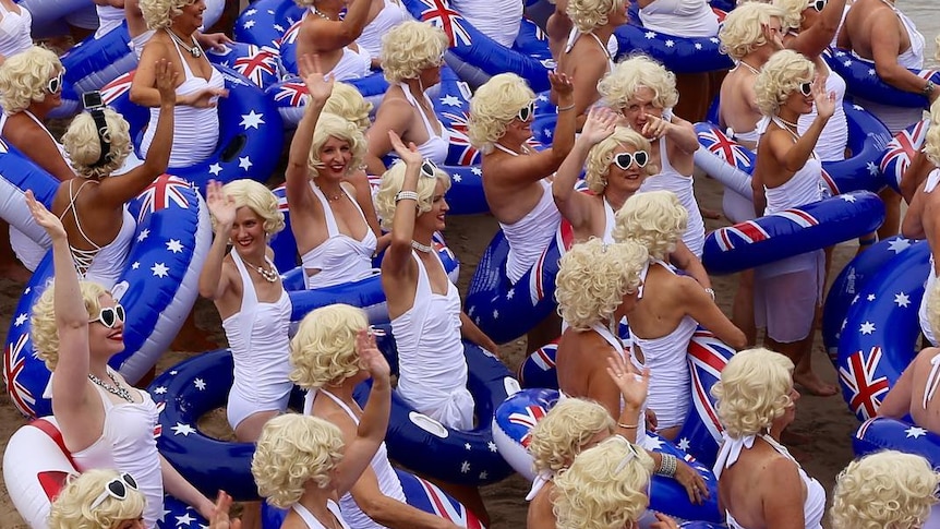 People in white swimsuits with Australian flag inflatable rings