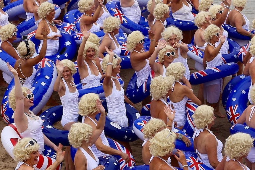 People in white swimsuits with Australian flag inflatable rings