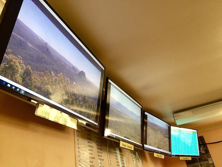 row of television screens hanging on walls in an incident control room