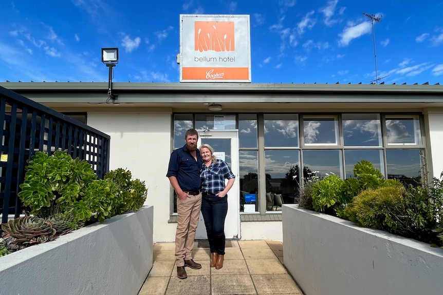 A man and a woman standing outside a modern-looking pub