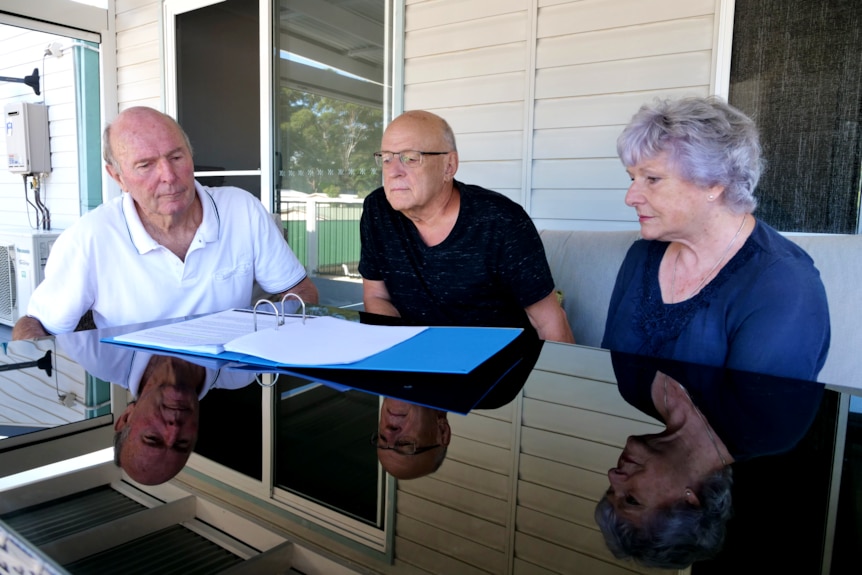 Three older people reading a document