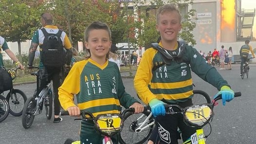 Two young boys in Australian uniforms standing with their BMX bikes.