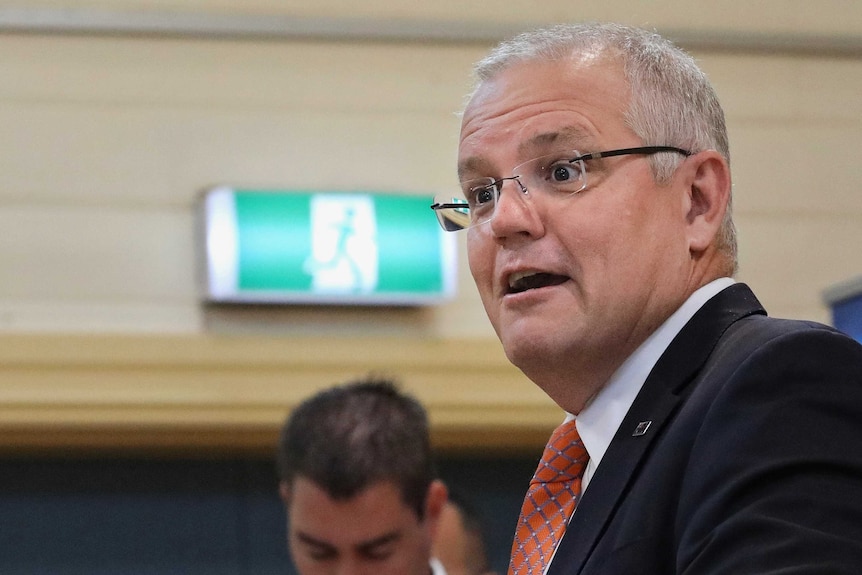 The Prime Minister is speaking with an exit sign above his right shoulder